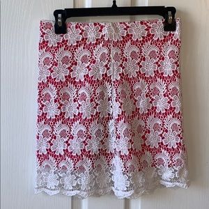 short pink skirt with white lace design over it.